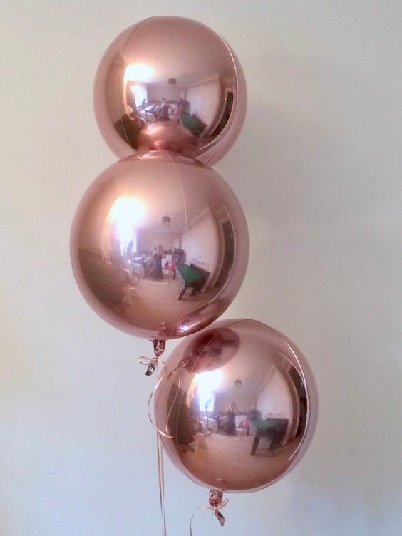 A bouquet of three rose gold orbz balloons