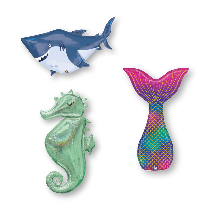 Three mylar sea creature balloons, including a smiling shark, a sea horse, and a mermaid tail